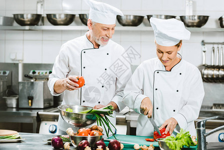穿双乳夹衣和戴帽子在餐厅厨房做饭的男女厨师图片