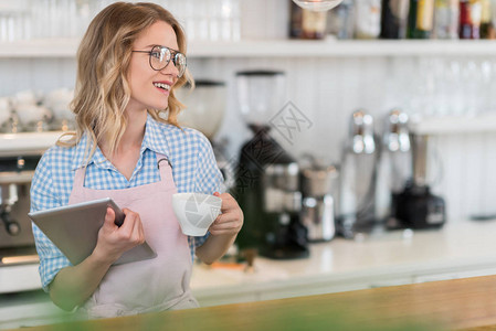 年轻笑的女服务员拿着平板和咖背景图片