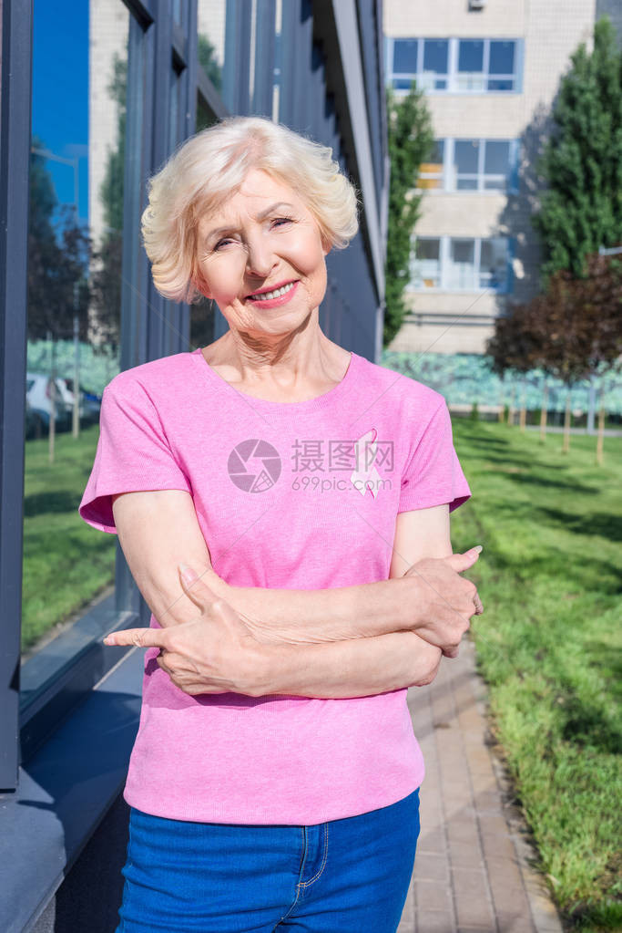 穿着粉红T恤的快乐老年妇女带着乳癌意识在镜头图片