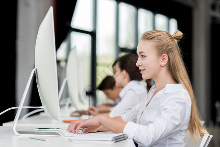 在课堂上学习时微笑的少女在电脑上工图片