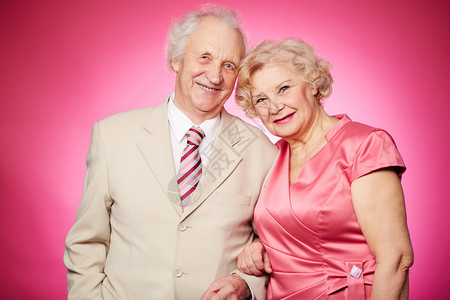 一对迷人的退休夫妇在粉红背景图片