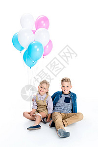 带着多彩气球的可爱小男孩与女孩坐在一起图片
