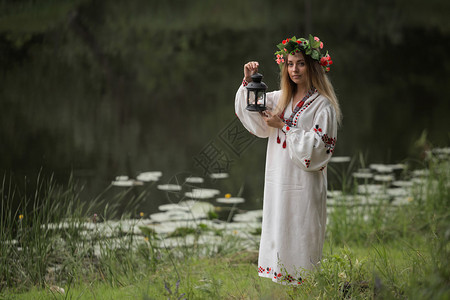 身着白俄罗斯传统花圈裙子的年轻美少女在水中用站立起来图片