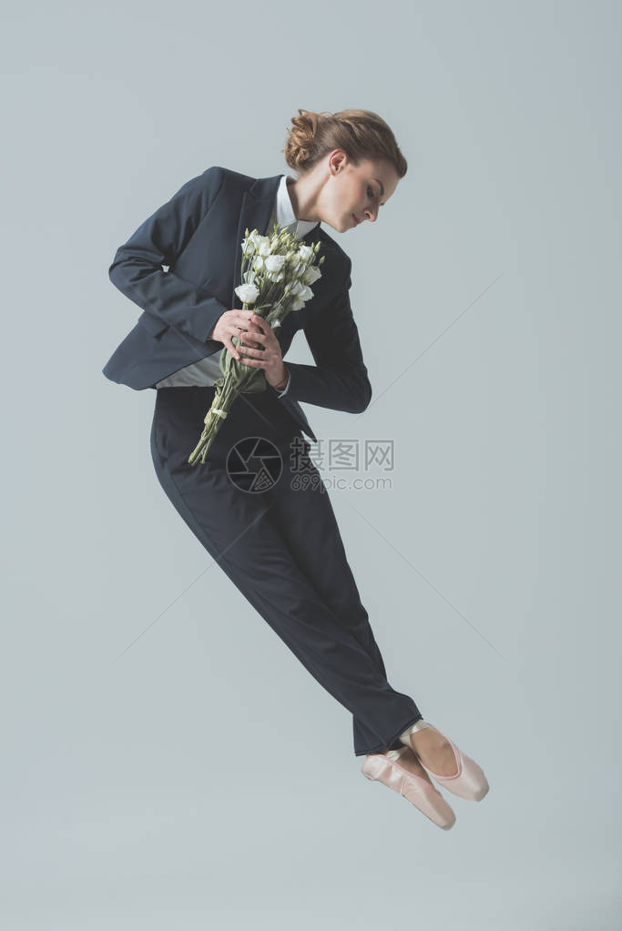 穿着西装和芭蕾舞鞋的女商人用花束跳跃图片