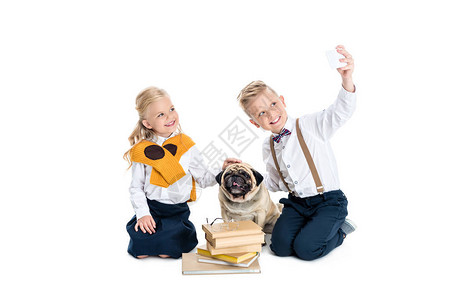 可爱的快乐的孩子玩狗和自拍用智能手机图片