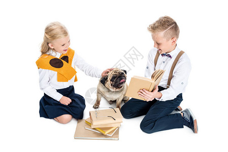 可爱的小孩在看书和玩狗却被图片