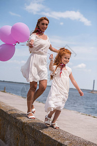 快乐的母亲和女儿带着气球同时在图片