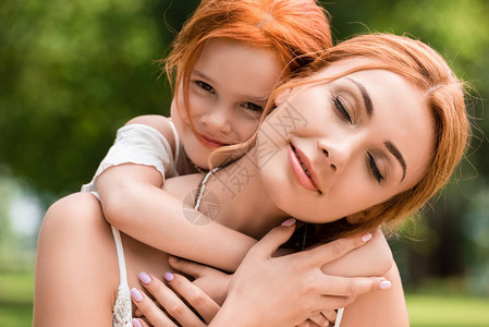 美丽的红发母亲和女儿在公园抱图片