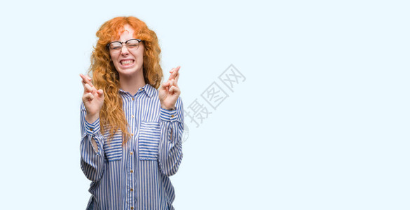 年轻红发女公交员微笑着满怀希望的交叉手指图片