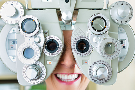 在光学或眼科医生进行眼视测试的霍普特年轻女图片