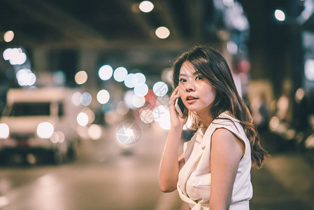 美丽的亚洲女在夜间与智能手机交谈图片