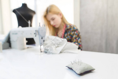 在缝纫机和人体模型上工作的女裁缝的背景下图片