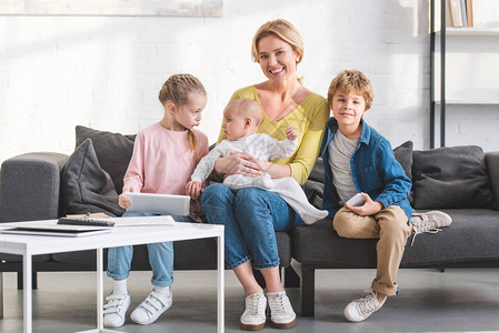 与三个可爱孩子坐在沙发上时快乐的母亲图片