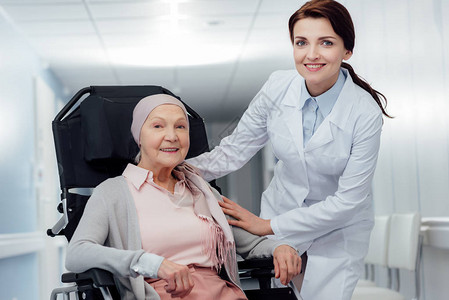 美丽快乐的女医生在医院坐在轮椅上戴着头巾图片