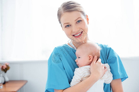 快乐的年轻母亲抱着新生婴儿在医院房间里图片