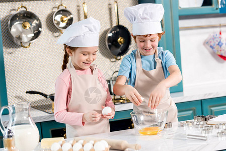 穿着厨帽和围裙的可爱笑着孩子在厨房图片