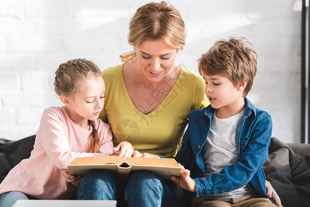 带着可爱的孩子在家一起看书的幸福母亲图片