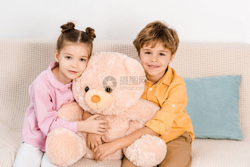可爱的快乐的孩子拥抱着粉红泰迪熊图片