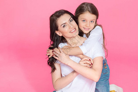 快乐的美丽的母亲和女儿坐在一起拥抱着粉红图片