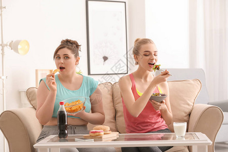 妇女在家里吃饭在饮食与不健康食品图片