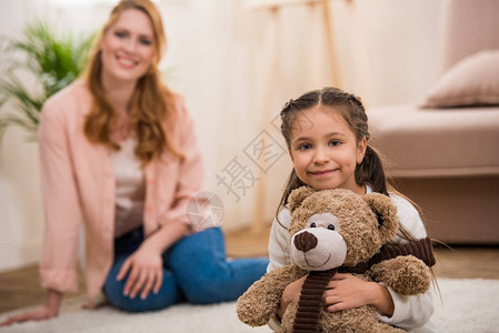 可爱的小孩抱着泰迪熊笑着对镜头微笑而妈图片