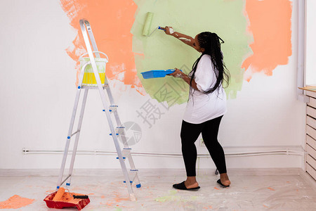 快乐的非洲裔美国女人在她的新公寓里画墙装修重新装背景图片