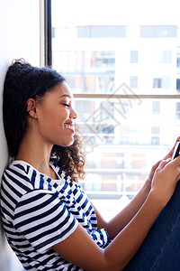 年轻黑人女子看手机的侧面肖像图片