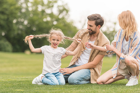 快乐的父母看着可爱的小女儿在公园里玩得开心图片