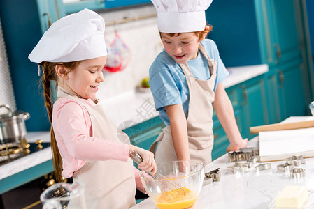 可爱的笑着孩子在厨师帽子和围裙上一图片