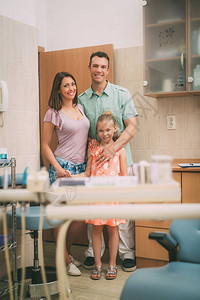 快乐的年轻家庭在看牙医办公室时站立图片