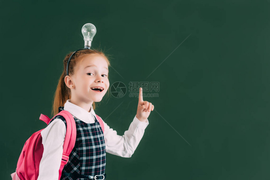 带着背包和灯泡的可爱快乐的学童头部用手指举起手指图片
