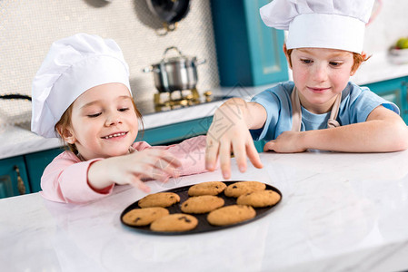 坐在厨帽上快乐的小孩在厨图片