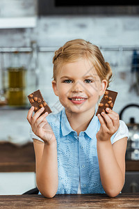 可爱的快乐的孩子拿着一块美味巧克力图片