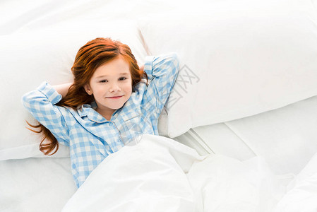 穿着睡衣的可爱小孩躺在床上图片