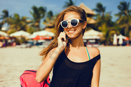 幸福快乐的女人在海滩上用手机享受假期穿着夏布的美丽女人的阳图片