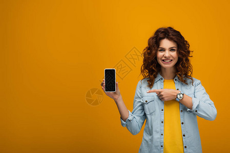 红发女人用手指着智能手机橙色上空白图片