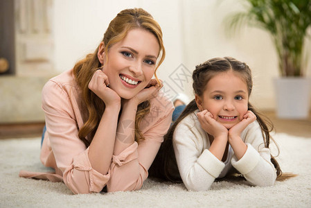 美丽的幸福母亲和女儿躺在地毯上图片