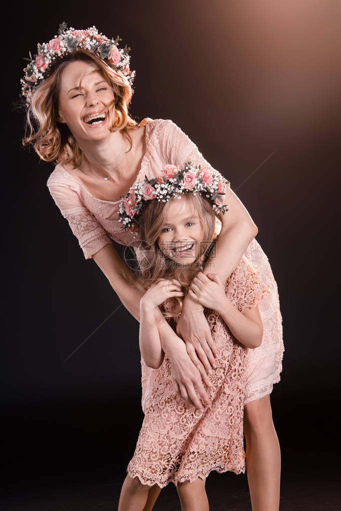 快乐的妈和女儿在花圈中拥抱并微笑着图片