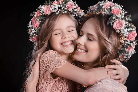 幸福的妈和女儿在花圈拥抱图片