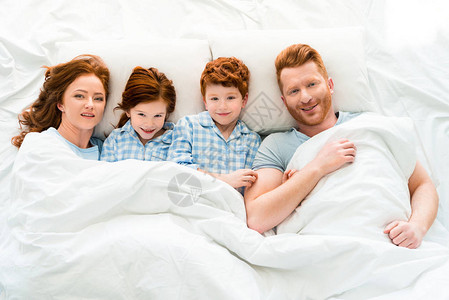 穿着睡衣的幸福家庭躺在床上图片