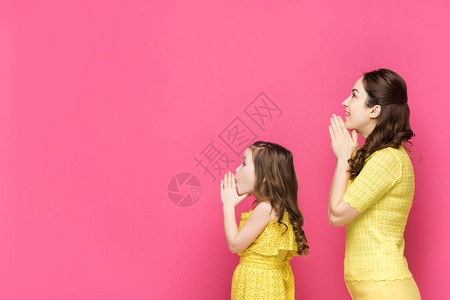 母亲和女儿在粉红色上孤立的图片