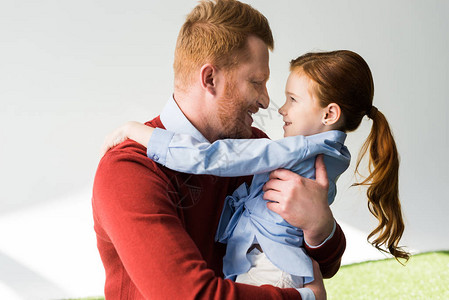 快乐的红发父亲和女儿在灰色图片