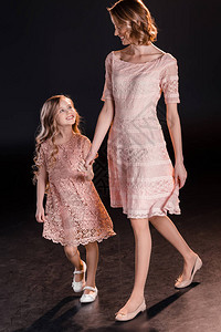 美丽的幸福母亲和女儿穿着粉红裙子走图片