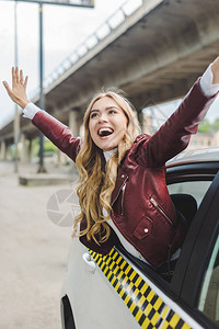 快乐的金发女孩举起手透过出租车图片