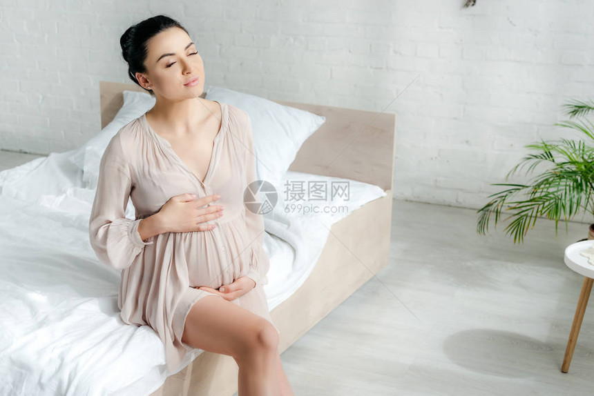 梦寐以求的孕妇穿着衣服坐在床图片