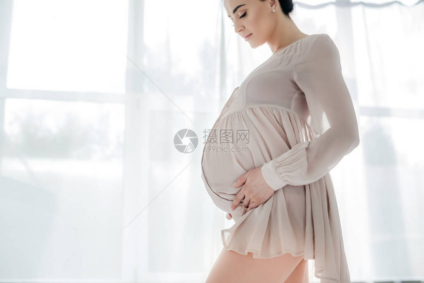 穿着睡衣的美丽快乐的孕妇在卧图片