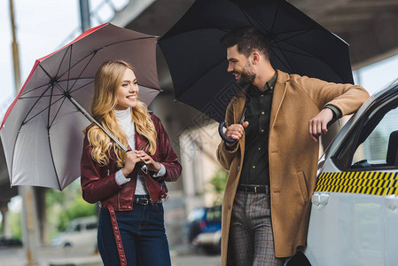 年轻一对快乐的情侣拿着雨伞图片