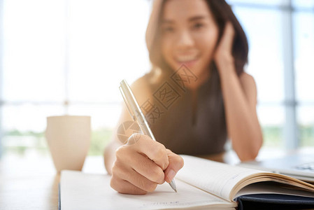 微笑的亚洲女学生在日记中写计划图片