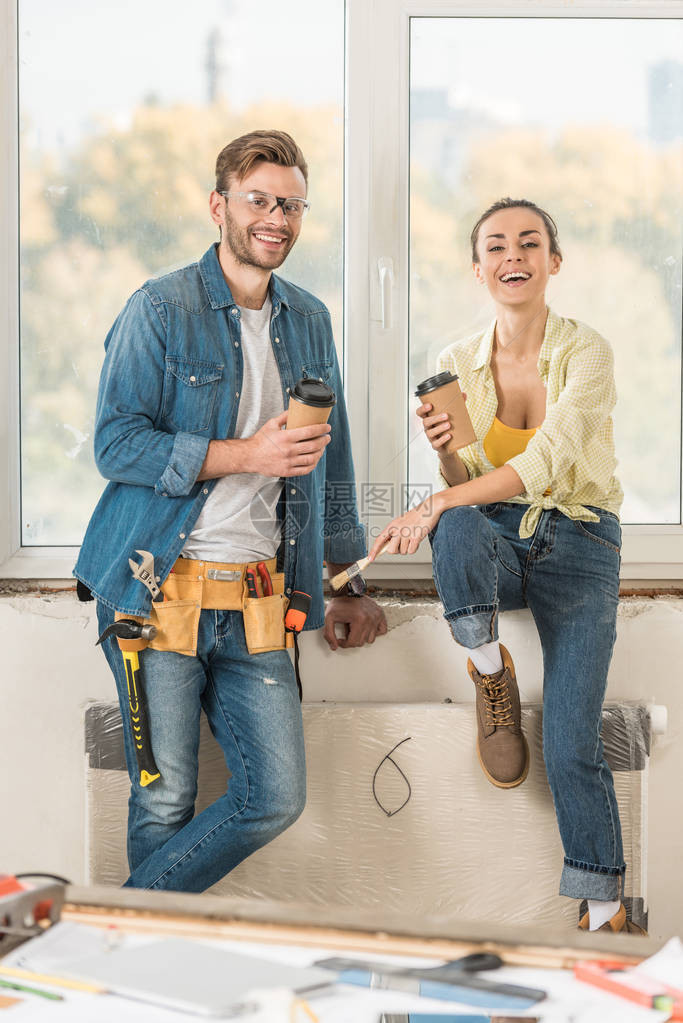 幸福的一对年轻夫妇拿着咖啡去修理房子时图片