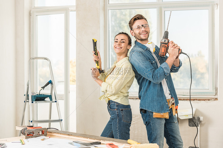 幸福的年轻夫妇拿着工具在修理房屋图片